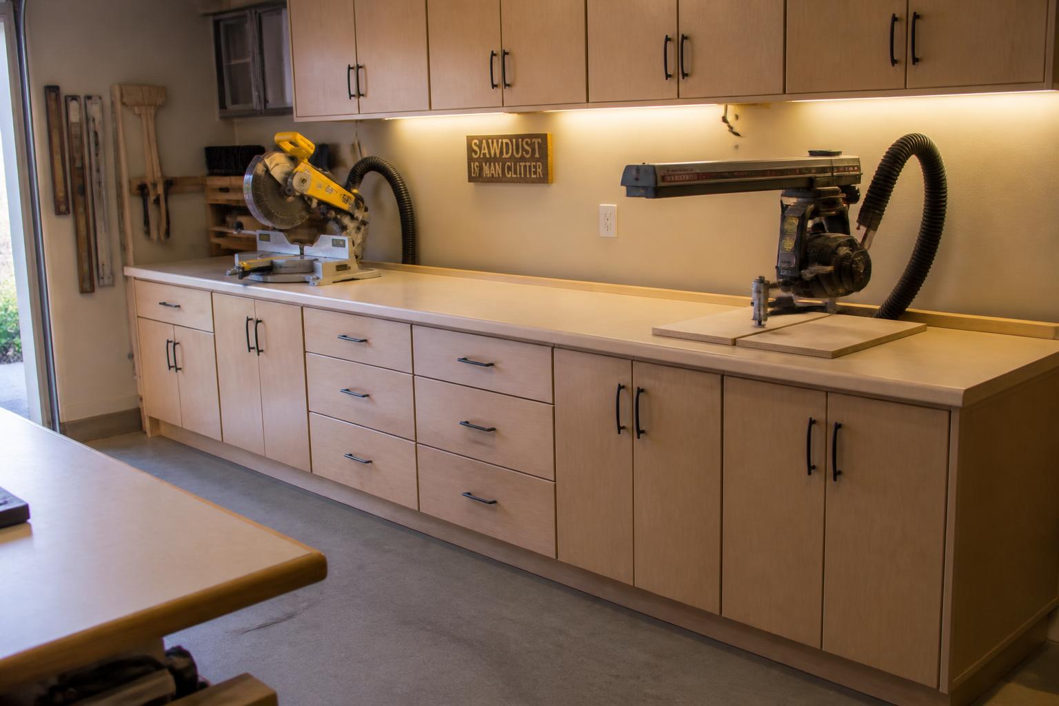 Finished 16-foot miter saw and radial arm saw station with drawers, doors, and dust hoses in place